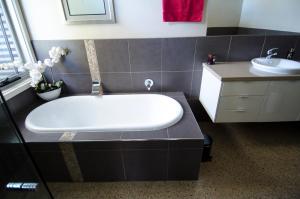 a bathroom with a tub and a sink at Corrugated Cottage in Dunkeld +19 photos