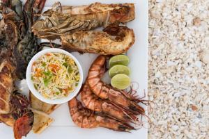 a plate of food with seafood and a bowl of coleslaw at Nungwi Dreams by Mantis in Nungwi