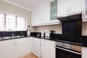 a kitchen with white cabinets and black appliances at La Pirogue 19 in Ballito