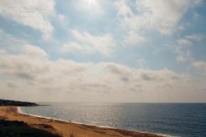 a beach with a cloudy sky and the ocean at Hotel Corsaro Nero in Portu Maga