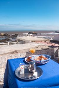 niebieski stół z talerzem jedzenia i drinka w obiekcie Home with a sea view w mieście As-Suwajra
