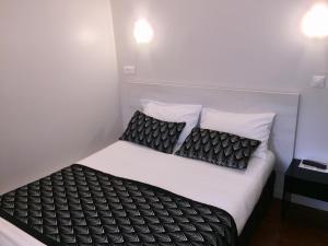 a bedroom with a bed with black and white pillows at Hôtel Vendôme in Aix-en-Provence