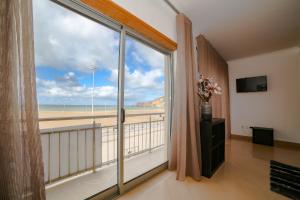 a room with a large window with a view of the beach at apartamentos Quebra-Mar in Nazaré