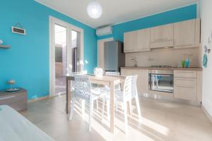 een keuken met blauwe muren en een tafel en stoelen bij Villa Viola in Torre Lapillo