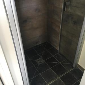 a shower with a glass door and a tile floor at Au coeur de la Flandre in Noordpeene