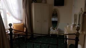 a bedroom with a bed with a mirror and a table at The Bay Guest House in Weymouth