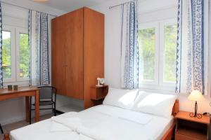 a bedroom with a bed and a desk and windows at O Pyrgos Accommodations in Panormos Skopelos
