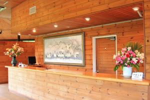a wooden lobby with a counter with flowers on it at Shomarutoge Garden House in Hanno