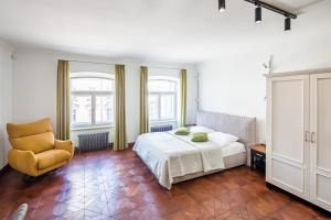 a bedroom with a bed and a yellow chair at Romari апартименти площа Ринок in Lviv