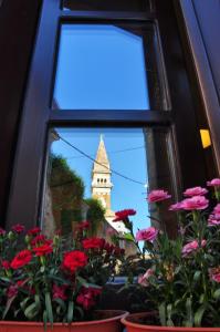 a window with a view of a clock tower and flowers at Max Piran in Piran