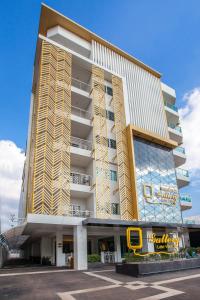 a tall building with a yellow chair in a parking lot at Gallery Lake View Hotel in Khon Kaen