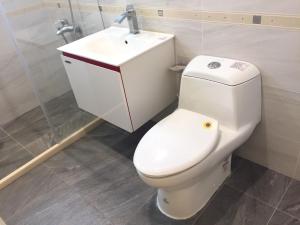 La salle de bains est pourvue de toilettes blanches et d'un lavabo. dans l'établissement Xiaodonglin Homestay, à Jinning