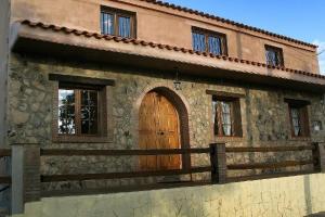 un edificio con una puerta de madera y una valla en Casa Rural Balcón del Camino Viejo en Valencia de Alcántara