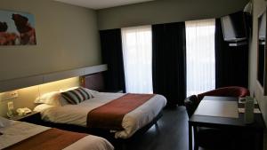 エデゲムにあるDe Basiliekのベッド2台とデスクが備わるホテルルームです。