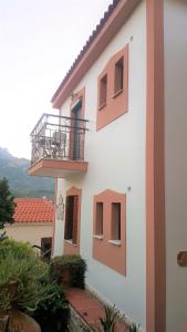 a white building with a balcony on the side of it at Green Hill Studios & Apartments in Kokkari