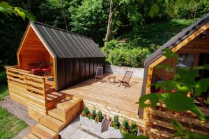 a small wooden cabin with a deck and two chairs at Penzion Šterk in Most na Soči