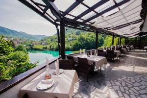 a restaurant with tables and chairs and a view of a river at Penzion Šterk in Most na Soči