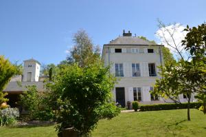 a large white house with a tower in the background at Le Clos Mademoiselle in Loches
