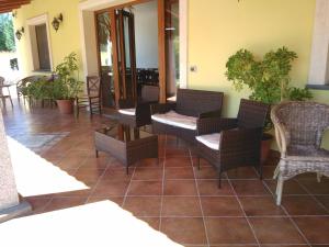 a patio with wicker chairs and tables on a tile floor at Agriturismo la Mimosa in Putzu Idu