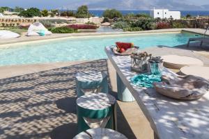 a table and chairs next to a swimming pool at Portes Houses in Koufonisia