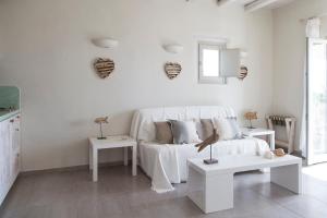 a white living room with a white couch and two tables at Portes Houses in Koufonisia