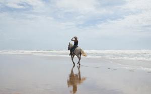 a person riding a horse on the beach at Pousada Capitù in Imbassai