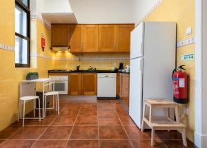a kitchen with wooden cabinets and a white refrigerator at Furadouro Surf Camp (House) in Ovar