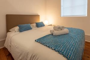 um quarto com uma grande cama branca com almofadas azuis em Furadouro Surf Camp (House) em Ovar