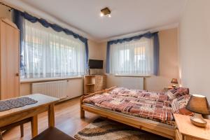 een slaapkamer met een bed, een bureau en 2 ramen bij Pokoje Gościnne Mrągowo in Mrągowo
