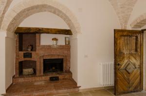 un camino in mattoni in una stanza con porta in legno di Masseria Mazzalorsa ad Alberobello
