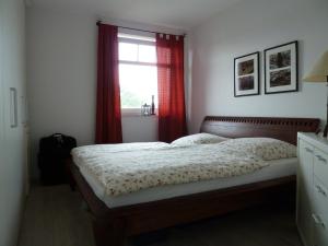 ツィノヴィッツにあるHaus Roland Wohnung 33のベッドと赤いカーテンの窓がある寝室 +14枚の写真