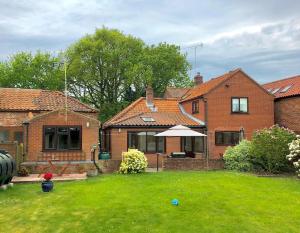 a house with a yard with an umbrella at The Earsdon Annexe in North Walsham
