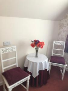 a table with a vase of flowers and two chairs at Wimberley House in Inverness