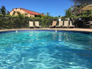 a swimming pool with chairs and an umbrella at Maui-LICIOUS by the Beach in Kihei