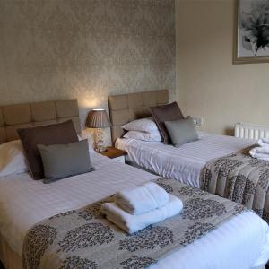 Dos camas en una habitación con toallas. en Melbourne Guest House, en Bowness-on-Windermere