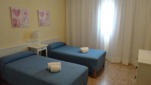 
two beds in a room with a blue wall at Apartamentos Cala Llonga in Cala Llonga
