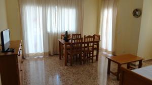 a dining room with a table and chairs and curtains at Apartamentos Cala Llonga in Cala Llonga