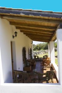 un patio con sedie, tavoli e tetto in legno di La Casa Del Poeta a Aglientu