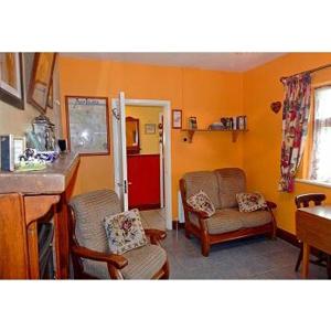 een woonkamer met 2 stoelen en een rode koelkast bij Hannah's Cottage in Farranfore
