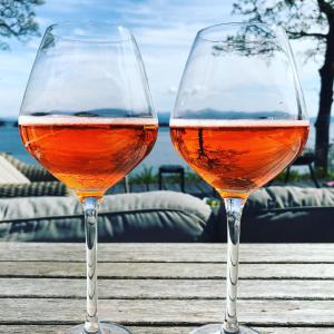 dos copas de vino sentadas en una mesa de madera en Villa Moldegaard Apartment, en Osøyro