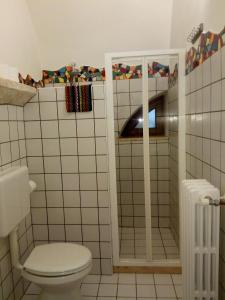 La salle de bains est pourvue de carrelage blanc, de toilettes et d'un radiateur. dans l'établissement B&b Altrov'è, à Parabita