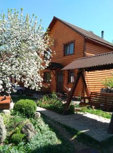 una casa de madera con un árbol florido delante de ella en Teremok en Mykulychyn