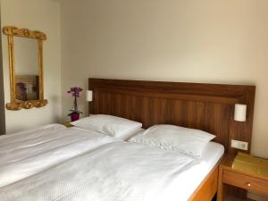 a large white bed with a wooden headboard and a mirror at Rupertihof in Fuschl am See