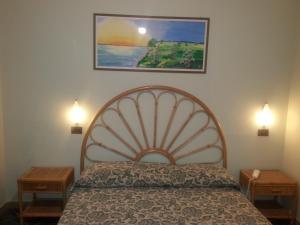 a bedroom with a bed with two night stands and a painting on the wall at Hotel Danila in Portoferraio