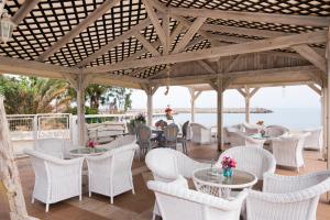 a patio with white chairs and tables and the ocean at Silver Sun Studios & Apartments in Malia