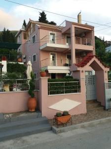 a pink apartment building with a balcony at Themis Apartments in Sami