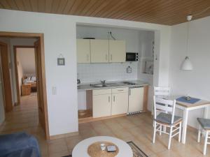 - une cuisine avec des placards blancs, une table et des chaises dans l'établissement Haus Strandgut/2, à Duhnen