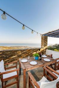 een houten tafel en stoelen met uitzicht op de oceaan bij Villa Tina in Arnados