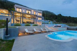 uma casa com piscina em frente a uma casa em Villa Blue Hill em Kaštela