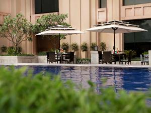 
a patio area with chairs, tables and umbrellas at The Metropolitan Hotel & Spa New Delhi in New Delhi
